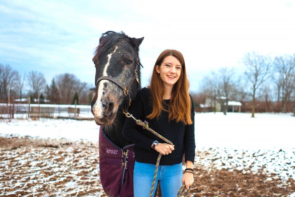 Keara and her horse, Storm, stand in the sunny, snowy fields of the Miami University equestrian center.