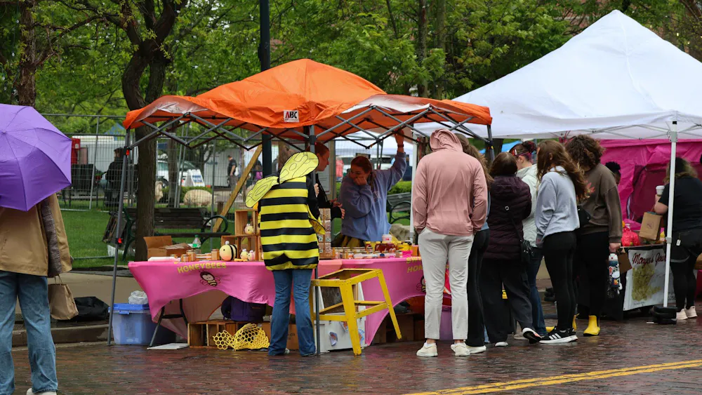 People stand by the honeybee booth during the Bee Festival.