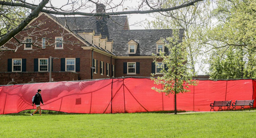 Student walks on Central Quad past construction site outside Hamilton Hall.