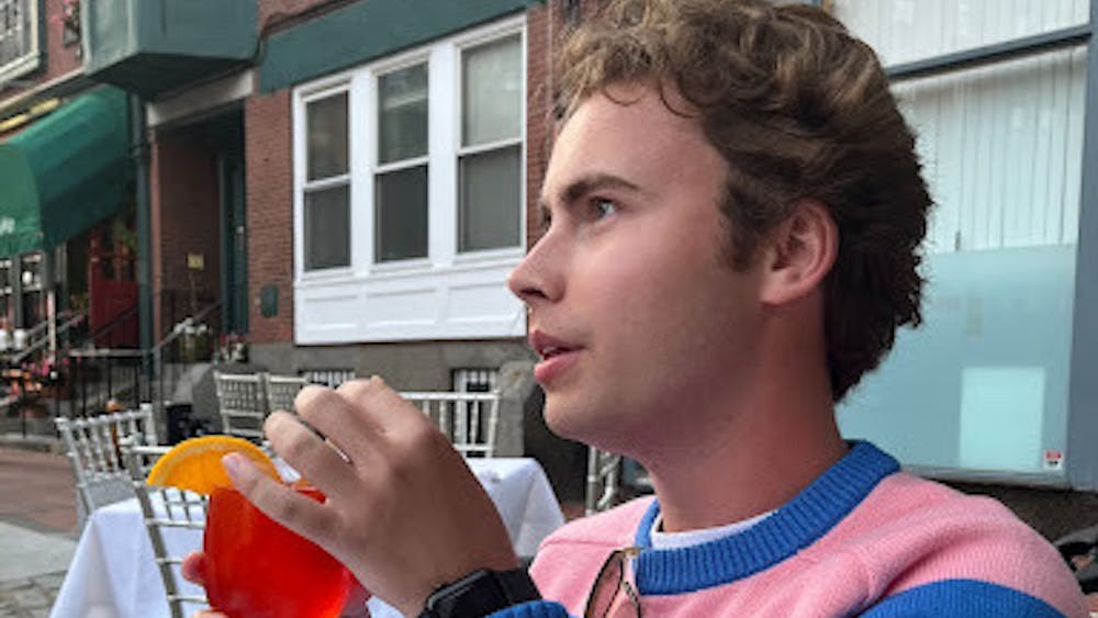Morrison wears a pink and blue striped sweater from J.Crew while having an aperol spritz in downtown Boston.