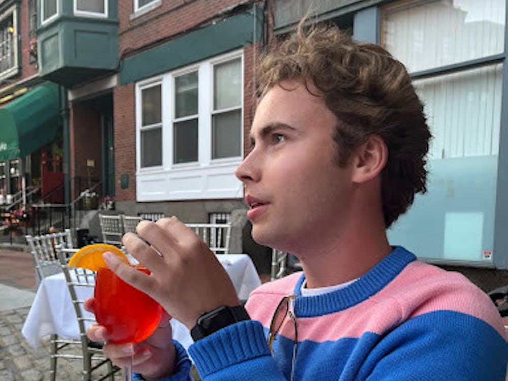Morrison wears a pink and blue striped sweater from J.Crew while having an aperol spritz in downtown Boston.
