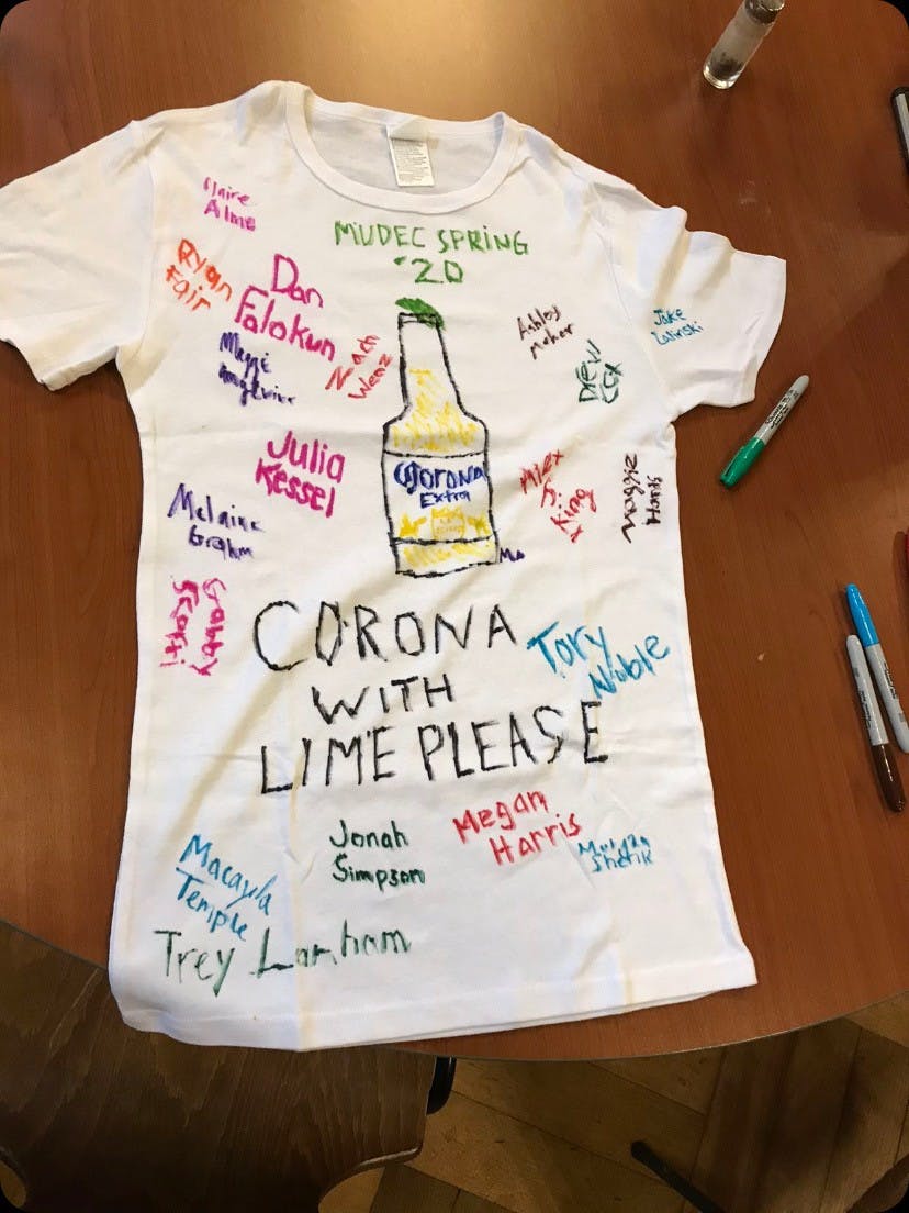 Per MUDEC tradition, each visiting class designs a t-shirt to be hung in the local college bar, Boot. This year&#x27;s t-shirt design reflected the students&#x27; reaction to leaving Luxembourg early due to the international novel coronavirus pandemic.