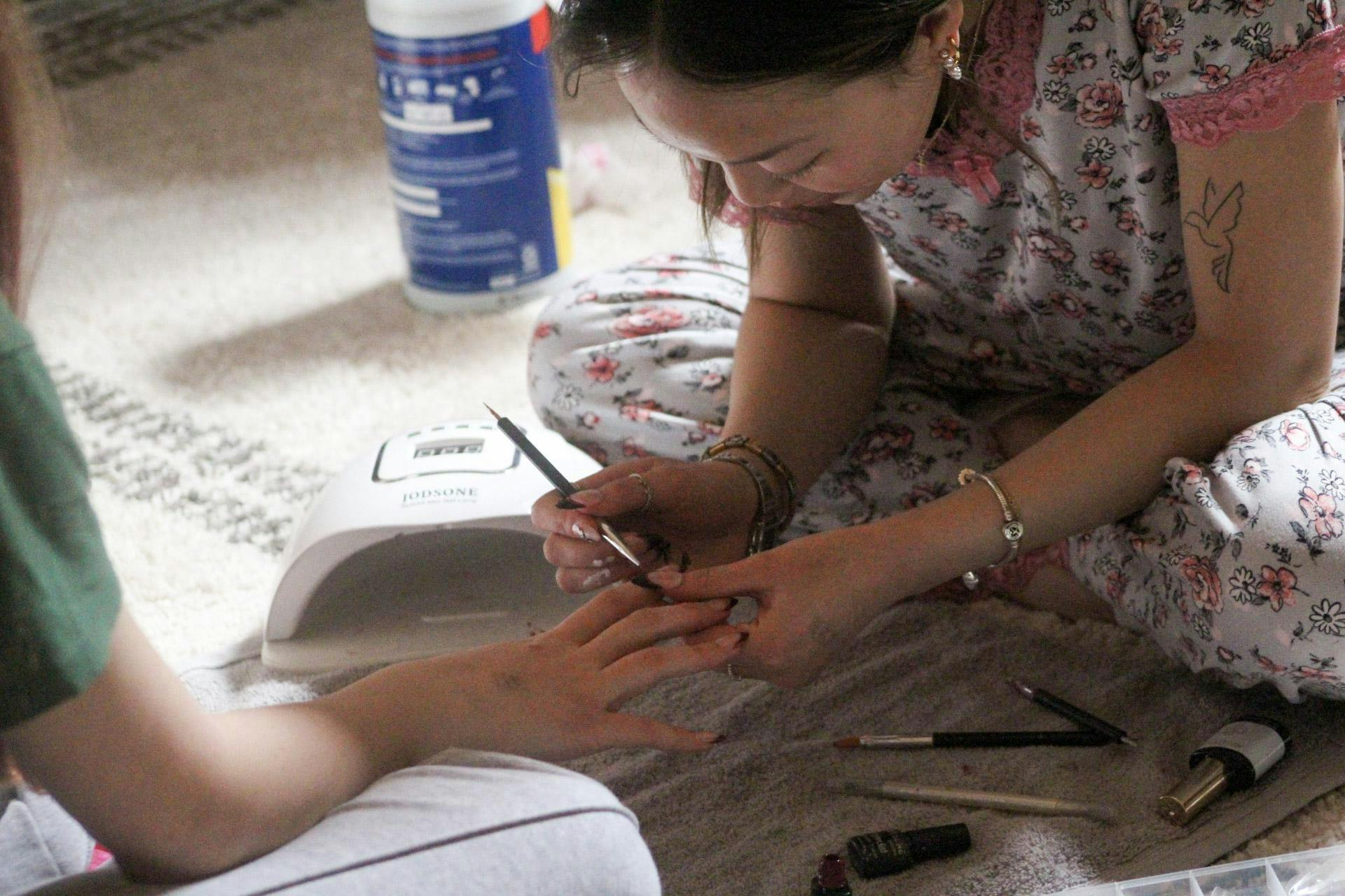 Ellie Davis painting a French tip nail design on a client in her dorm room
