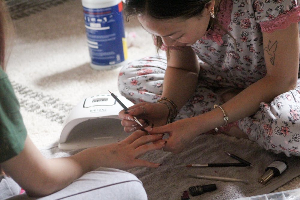 Ellie Davis painting a French tip nail design on a client in her dorm room