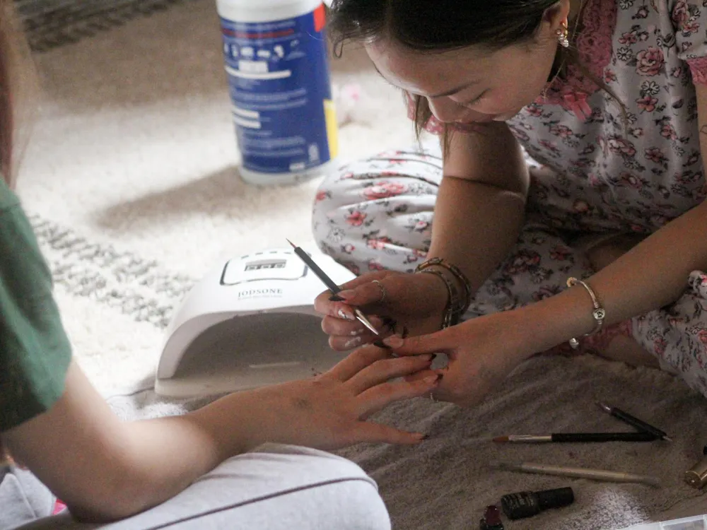 Ellie Davis painting a French tip nail design on a client in her dorm room