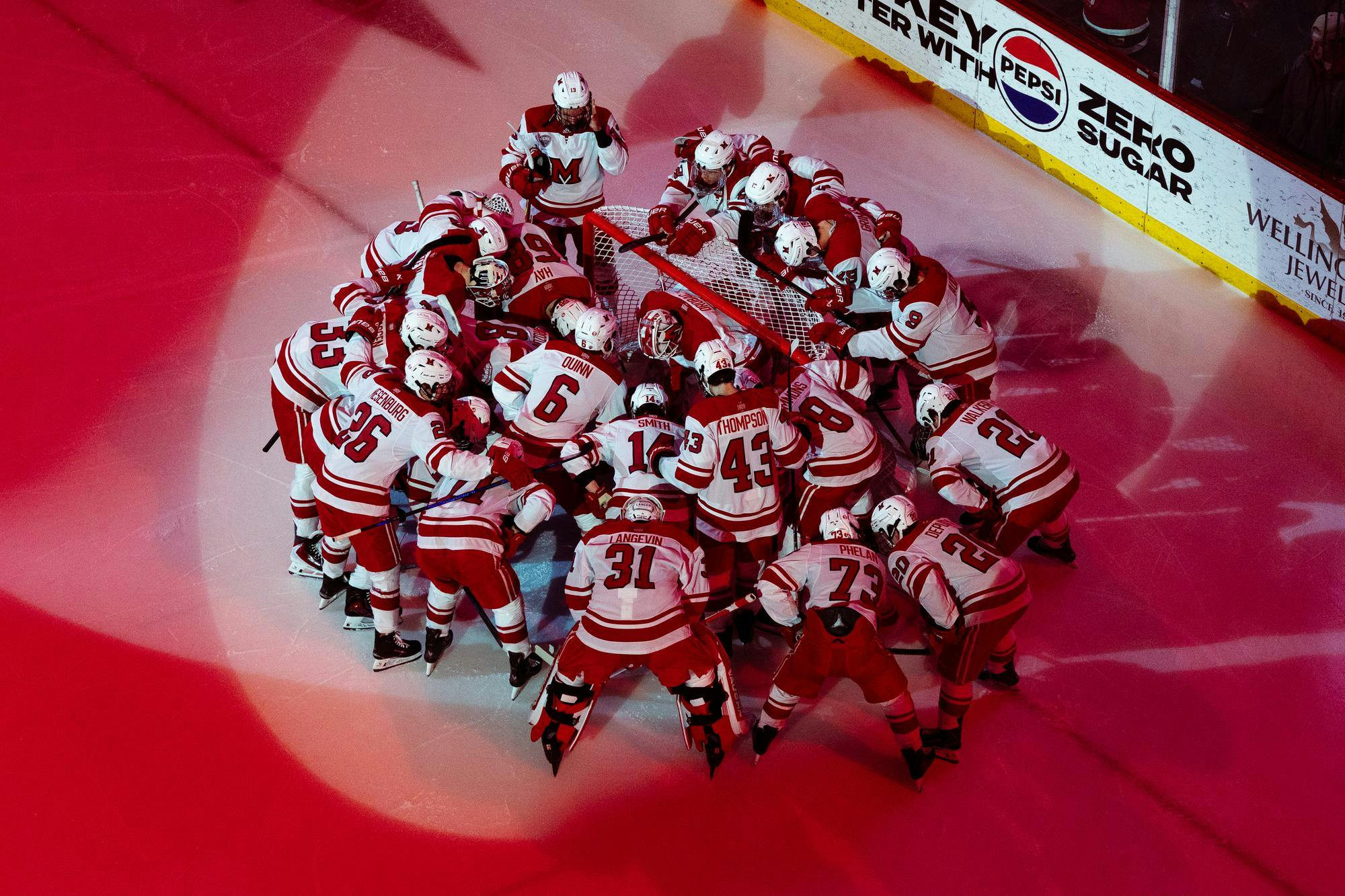 Miami hockey team huddles around the goalie at game against UMD. 