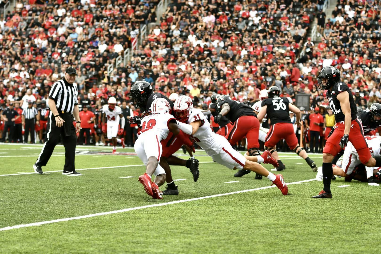 Veteran defensive backs Cedric Boswell (No. 18) and Sterling Weatherford (No. 21) combine for a tackle on a Cincinnati player. Weatherford intercepted a pass in Miami's 49-14 loss to the Bearcats.