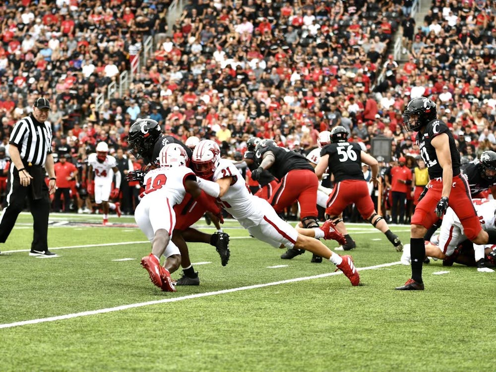Veteran defensive backs Cedric Boswell (No. 18) and Sterling Weatherford (No. 21) combine for a tackle on a Cincinnati player. Weatherford intercepted a pass in Miami's 49-14 loss to the Bearcats.