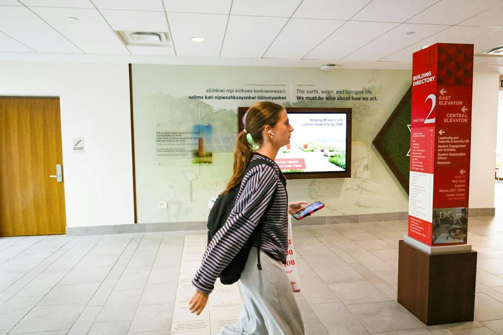 Student walking in front of the sustainability wall in Armstrong Student Center. 
