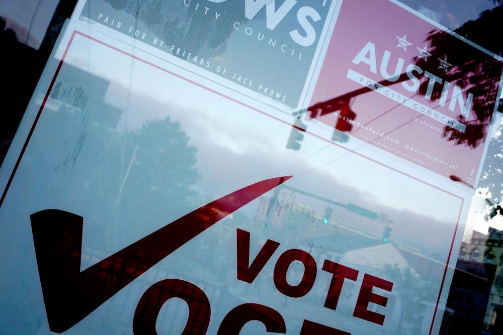 City Council campaign signs clustered together behind a storefront window in Uptown Oxford.