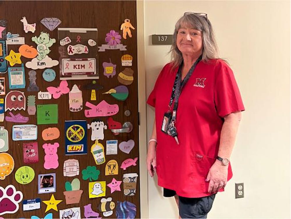 Building Grounds Associate Kimberly Durham in front of her supply closet, decorated by students and Resident Assistants in Hepburn Hall.