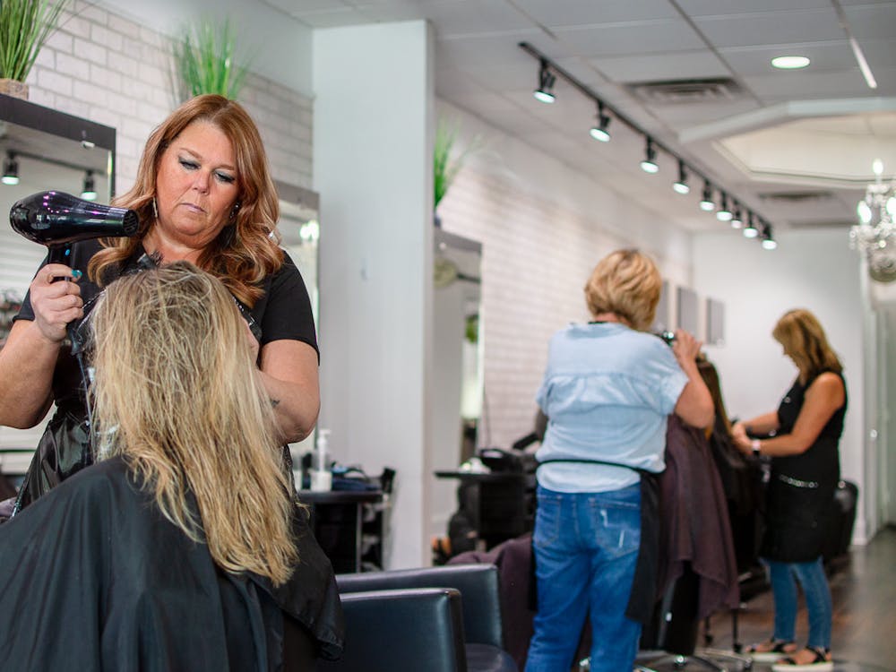 Hairdresser at Attitudes Uptown styling a client's hair.