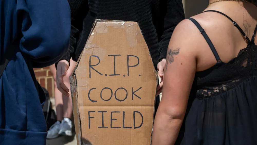 Student stands with cardboard coffin