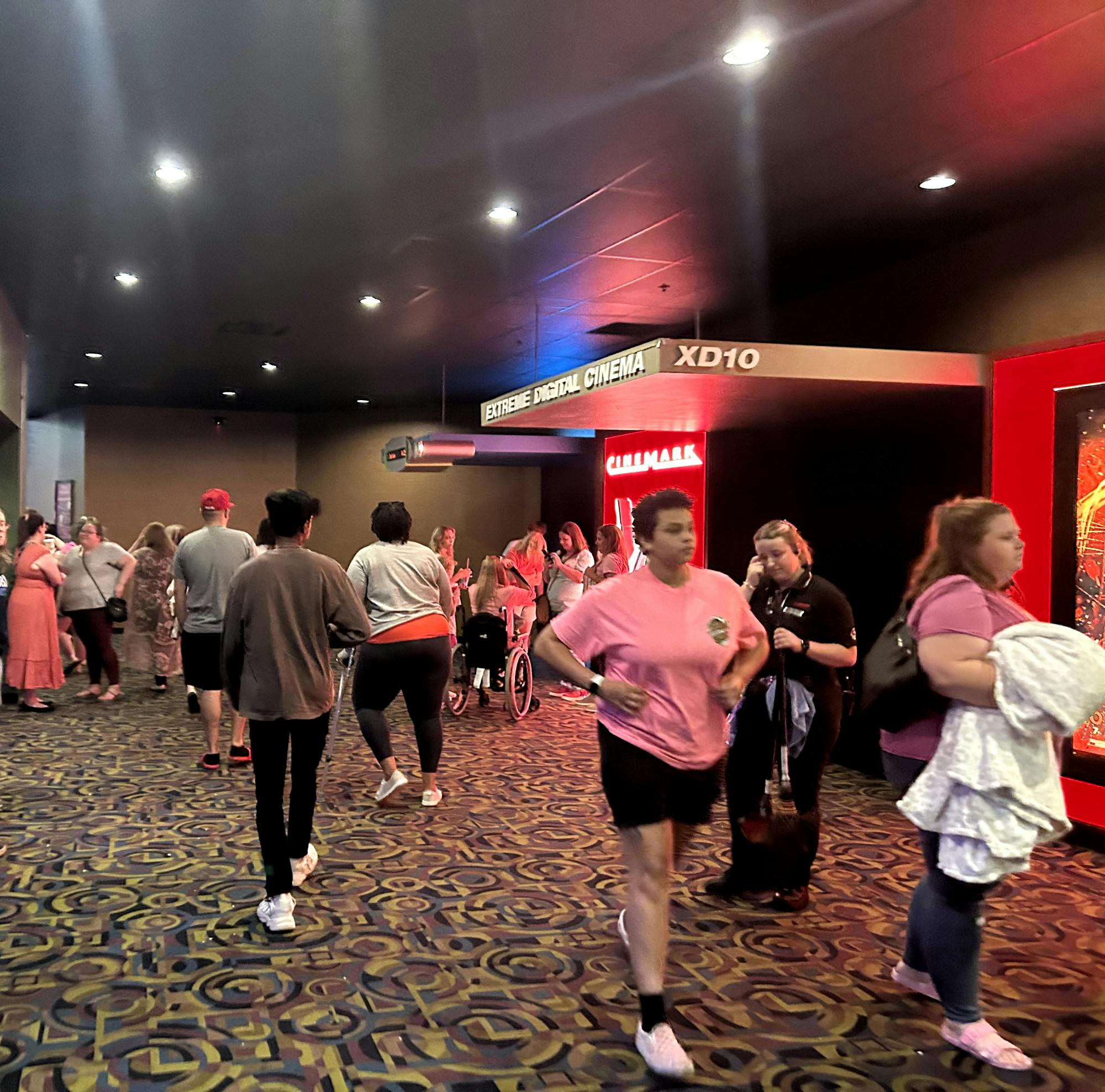 A crowd of moviegoers wait around in their pink outfits after seeing &quot;Barbie&quot;.