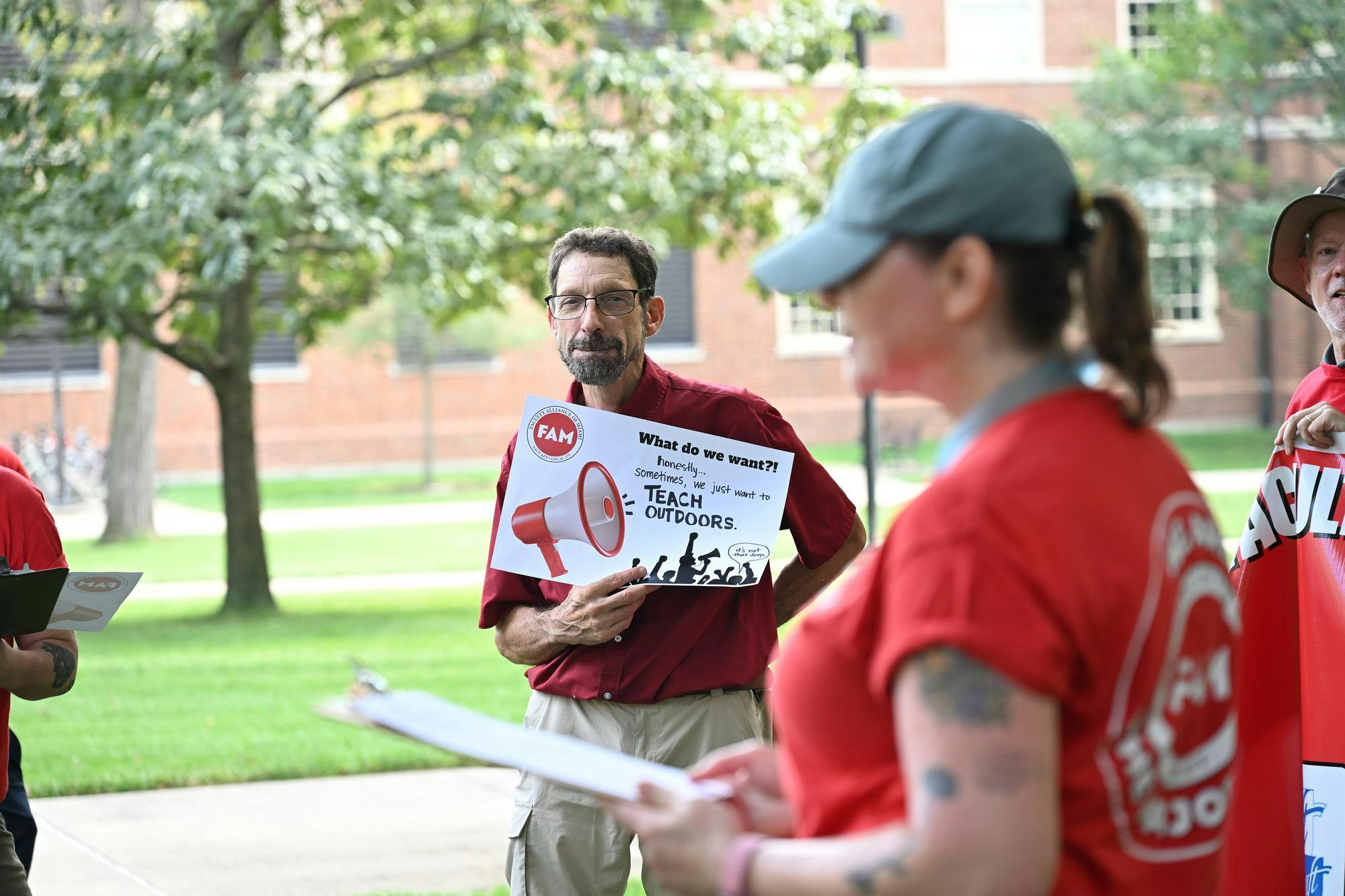 A Faculty Association of Miami member listens to another member at rally by the seal to fight for fair contracts for faculty and librarians.