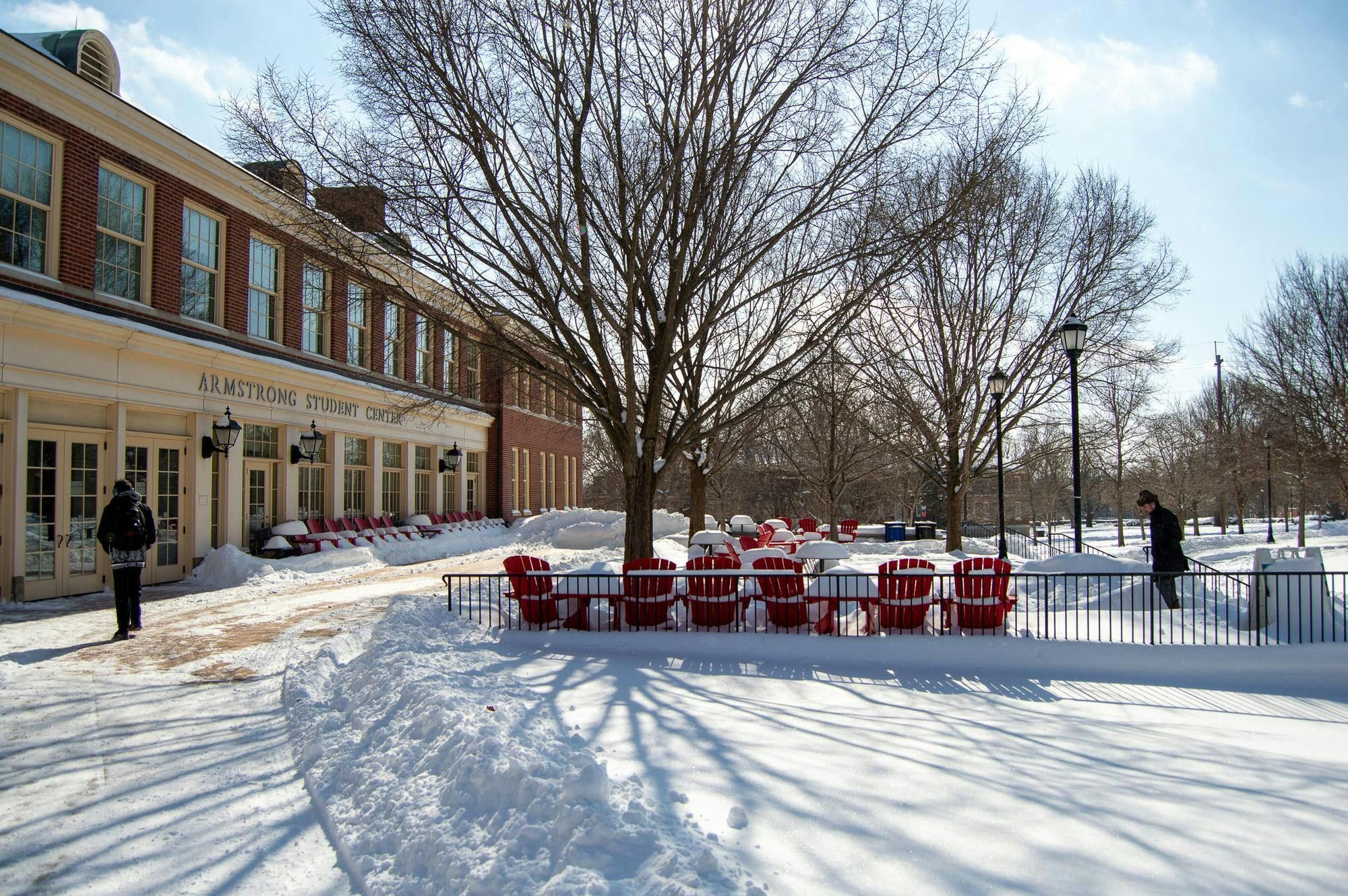 Two students walk into Armstrong Student Center in the snowy conditions. 