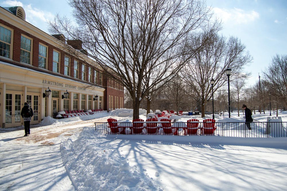 Two students walk into Armstrong Student Center in the snowy conditions. 