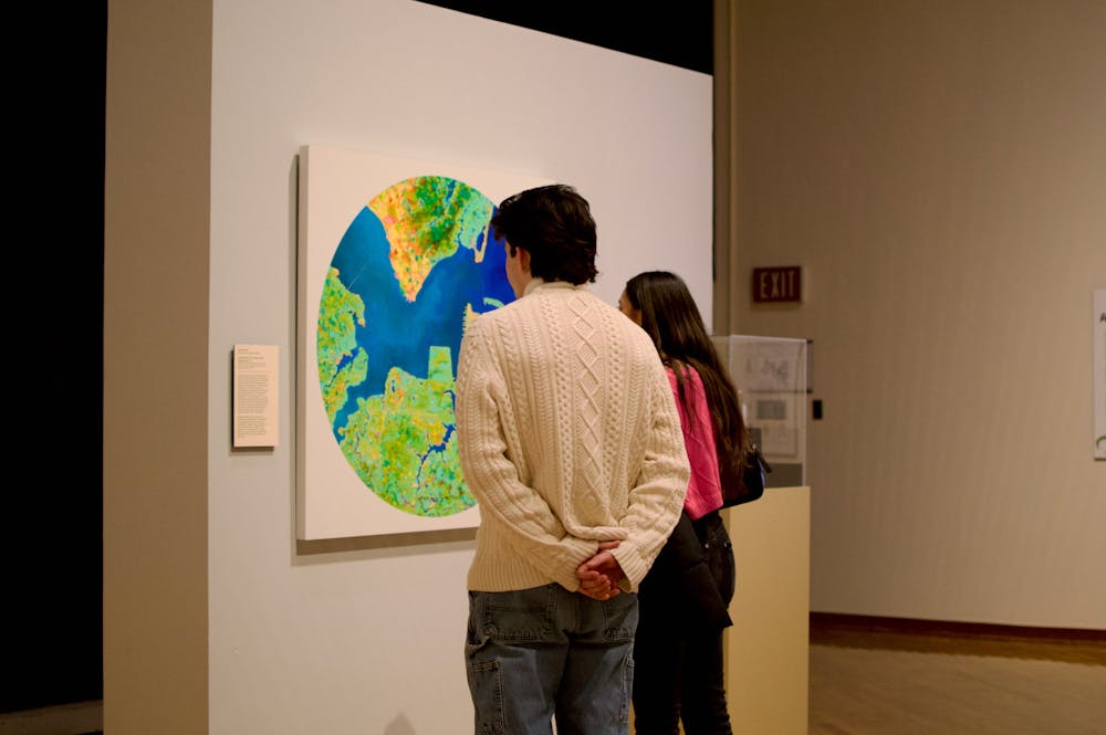 <p>Two museum-goers examine John Sabraw&#x27;s ﻿<em>Aerial Chroma S1 2</em>, which was painted using pigments extracted from residue left over from abandoned mines.</p>