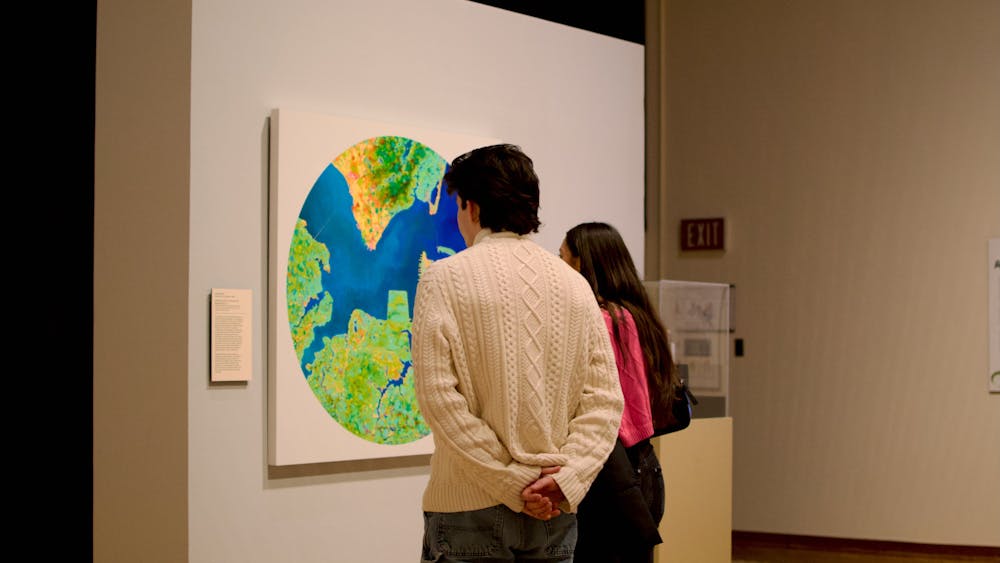 Two museum-goers examine John Sabraw&#x27;s ﻿Aerial Chroma S1 2, which was painted using pigments extracted from residue left over from abandoned mines.