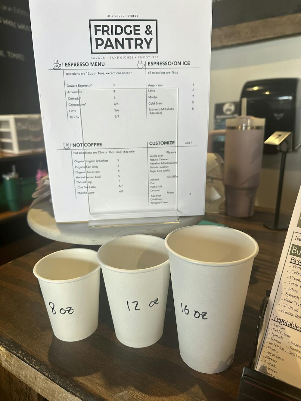 The menu for Fridge’s new espresso bar is featured at the register along with cups for reference to how big the sizes are.