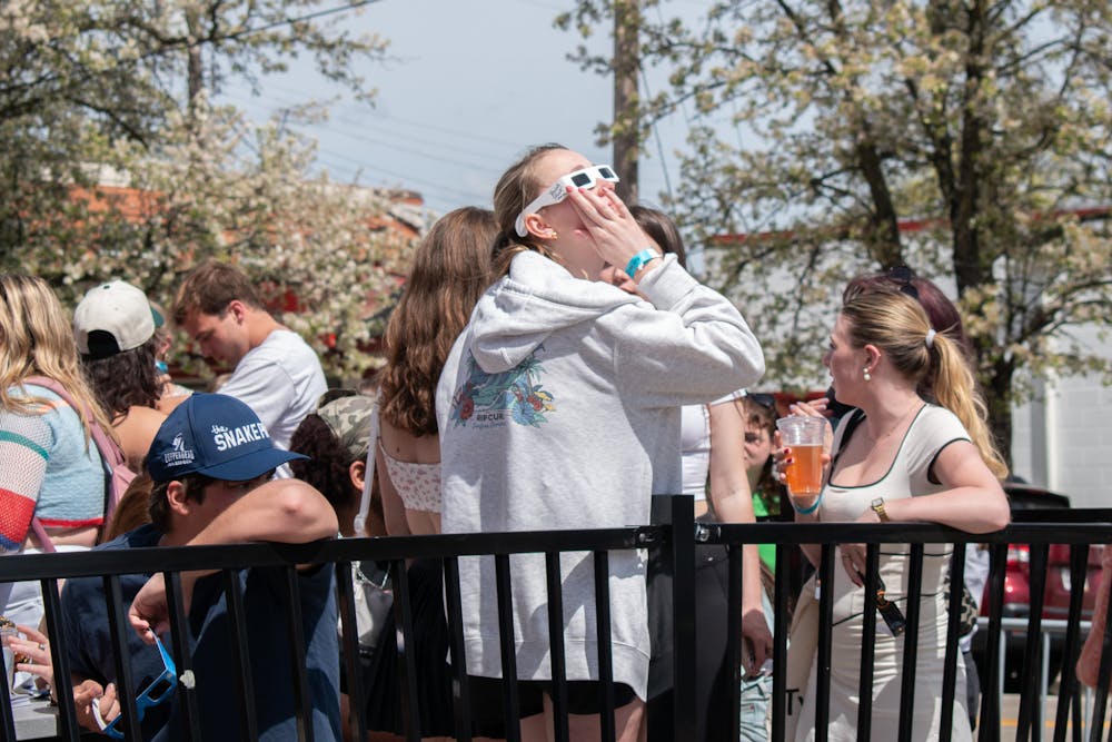 Students gather on Brick Street Bar's patio to observe the eclipse. 