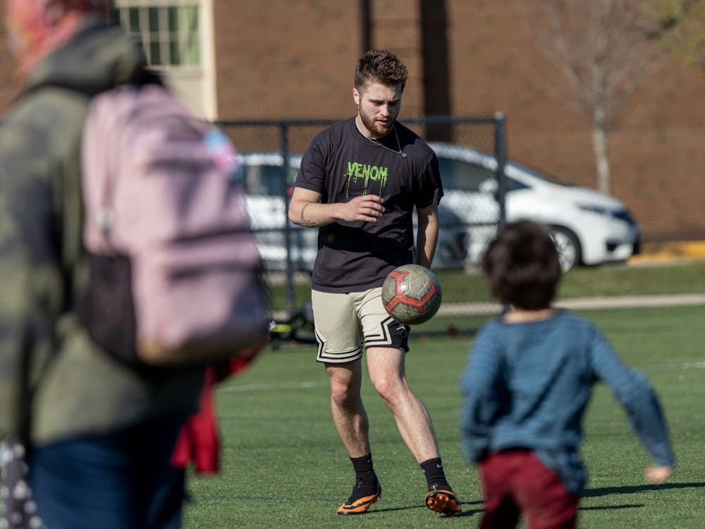A student controls a soccer ball passed by a friend on Cook Field by East Quad