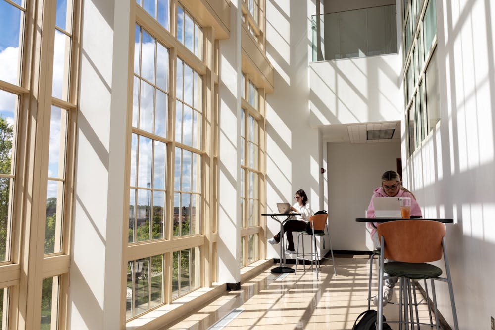 <p>Two students study upstairs next to the two-story windows in the Psychology Building.</p>
