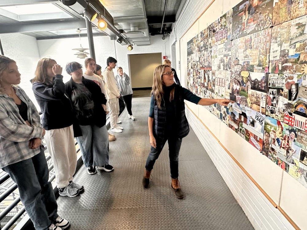 <p>Liz Martin, the department chair of architecture and interior design, views the Architecture 113 class's collages.</p>