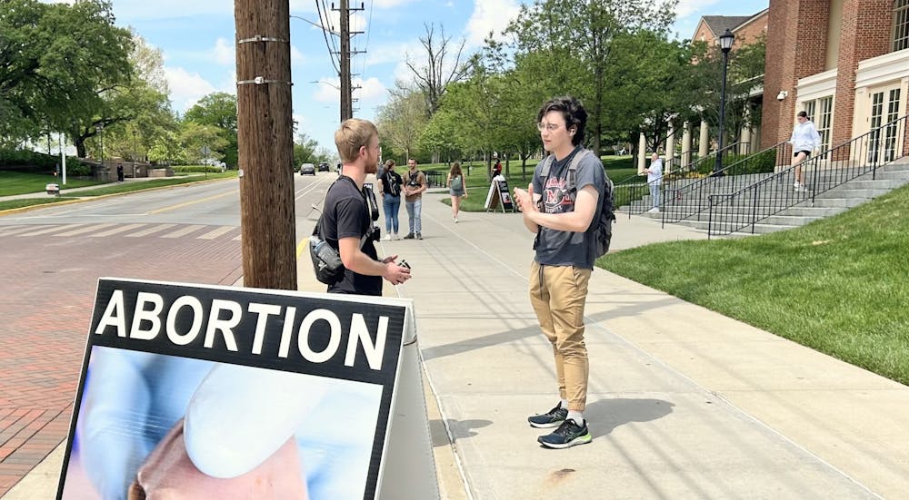 A student and a protestor talk in front of Armstrong Student Center.