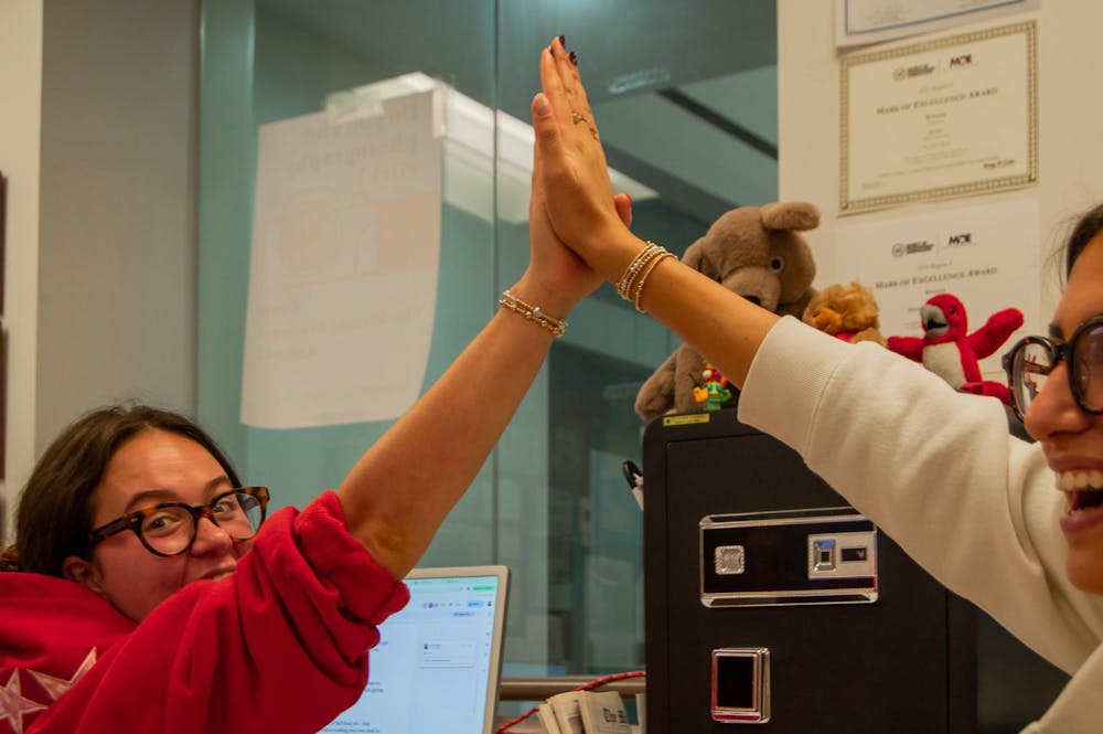 Anna Reier and Olivia Patel share a high-five during a production night in the TMS newsroom.