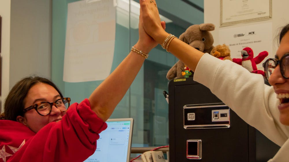 Anna Reier and Olivia Patel share a high-five during a production night in the TMS newsroom.