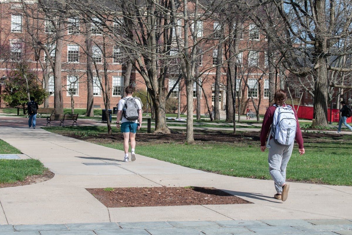Students walk past a dirt pit in the sidewalk where the Friendship Tree used to stand.