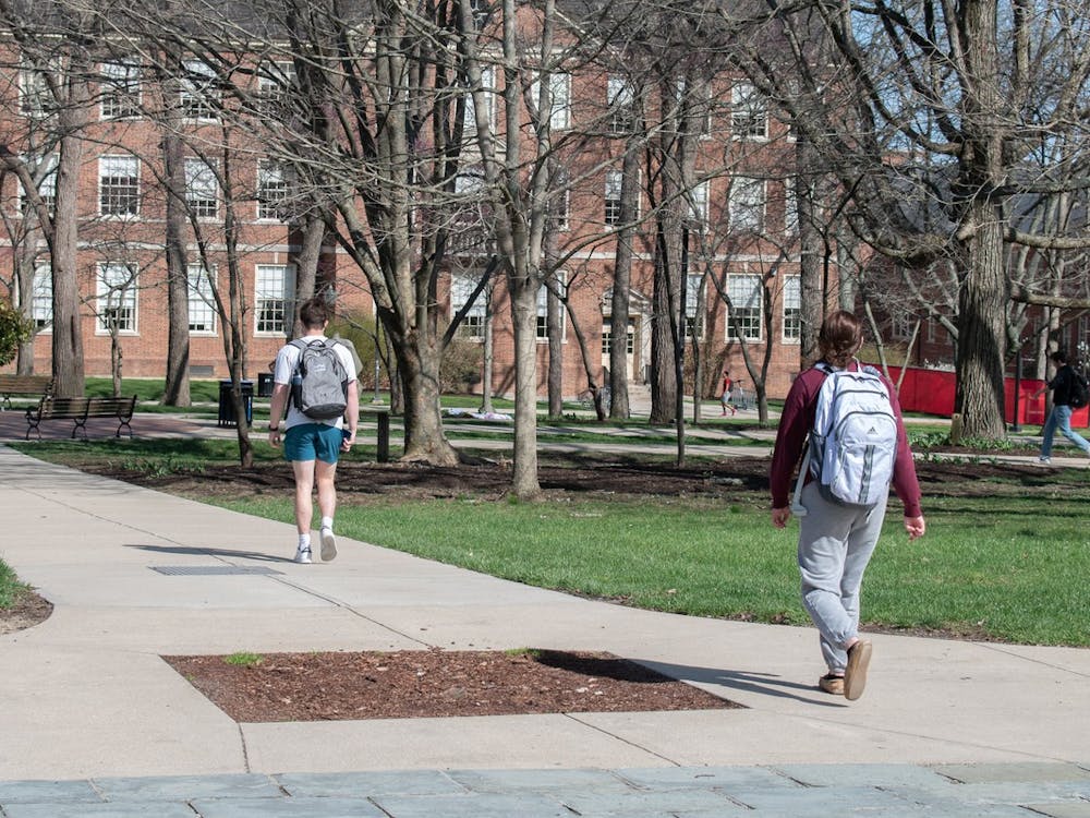Students walk past a dirt pit in the sidewalk where the Friendship Tree used to stand.