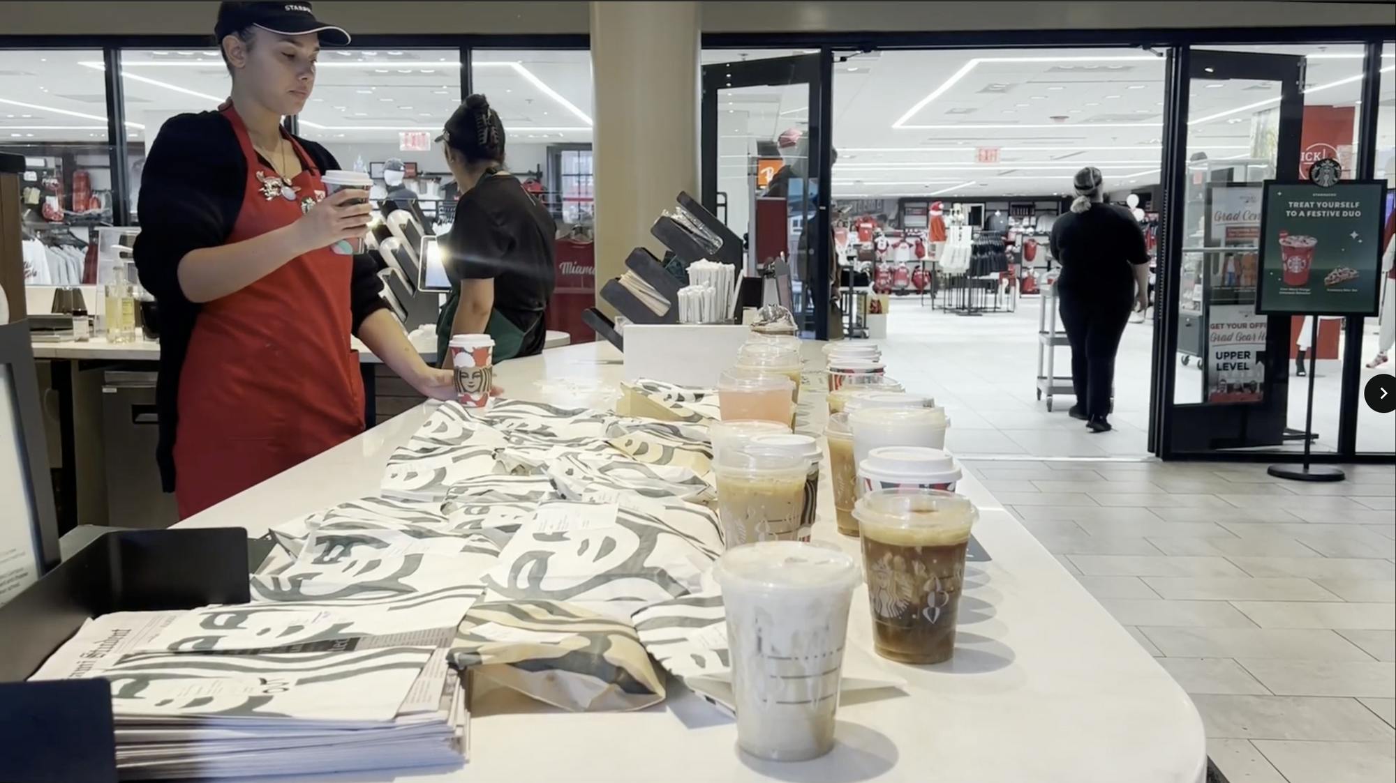 A Starbucks employee adds another drink to an full pickup counter.