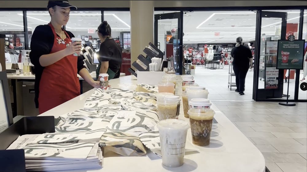 A Starbucks employee adds another drink to an full pickup counter.