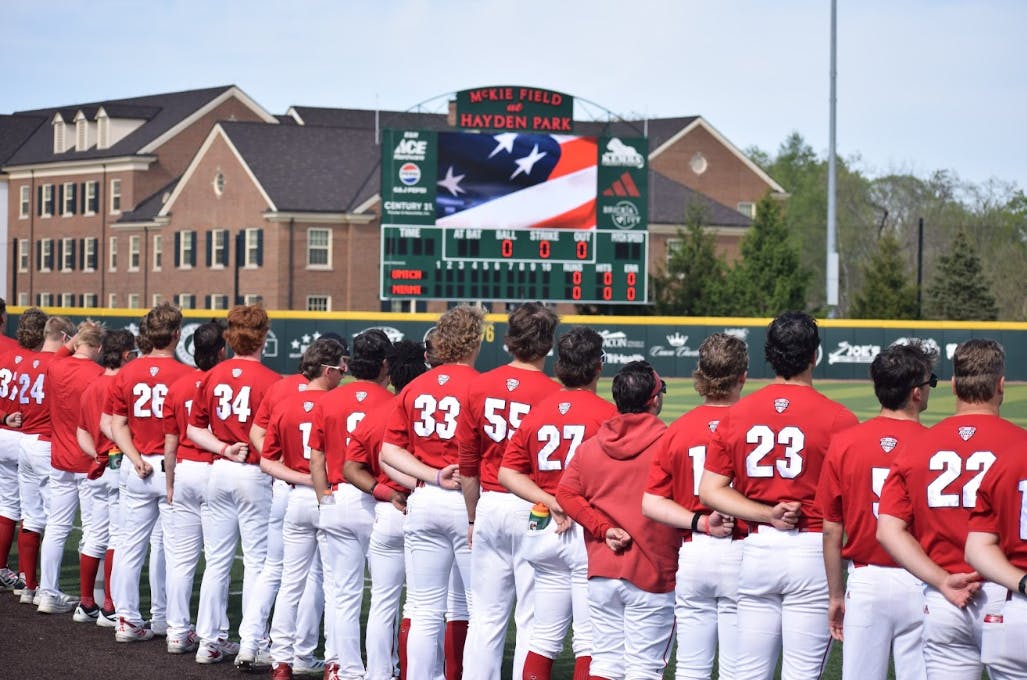 The Miami University RedHawks baseball team stands for the national anthem in game against the University of Michigan.