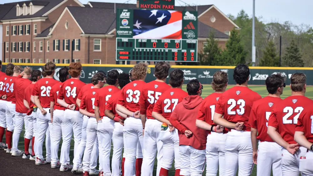 The Miami University RedHawks baseball team stands for the national anthem in game against the University of Michigan.