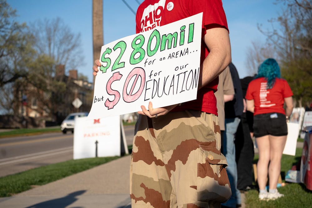 Student stands at the protest with a sign. Photo by Elise Hanna