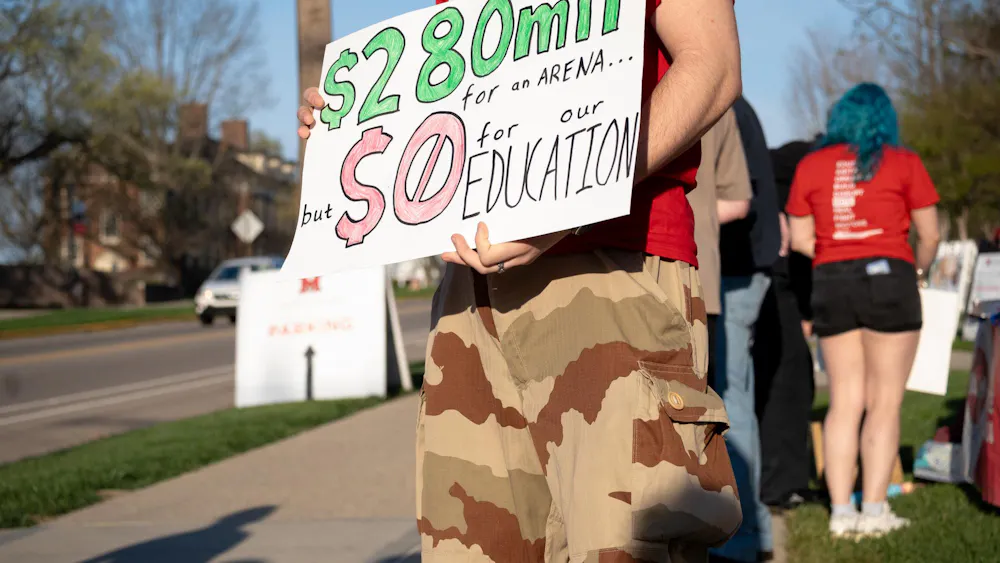 Student stands at the protest with a sign. Photo by Elise Hanna