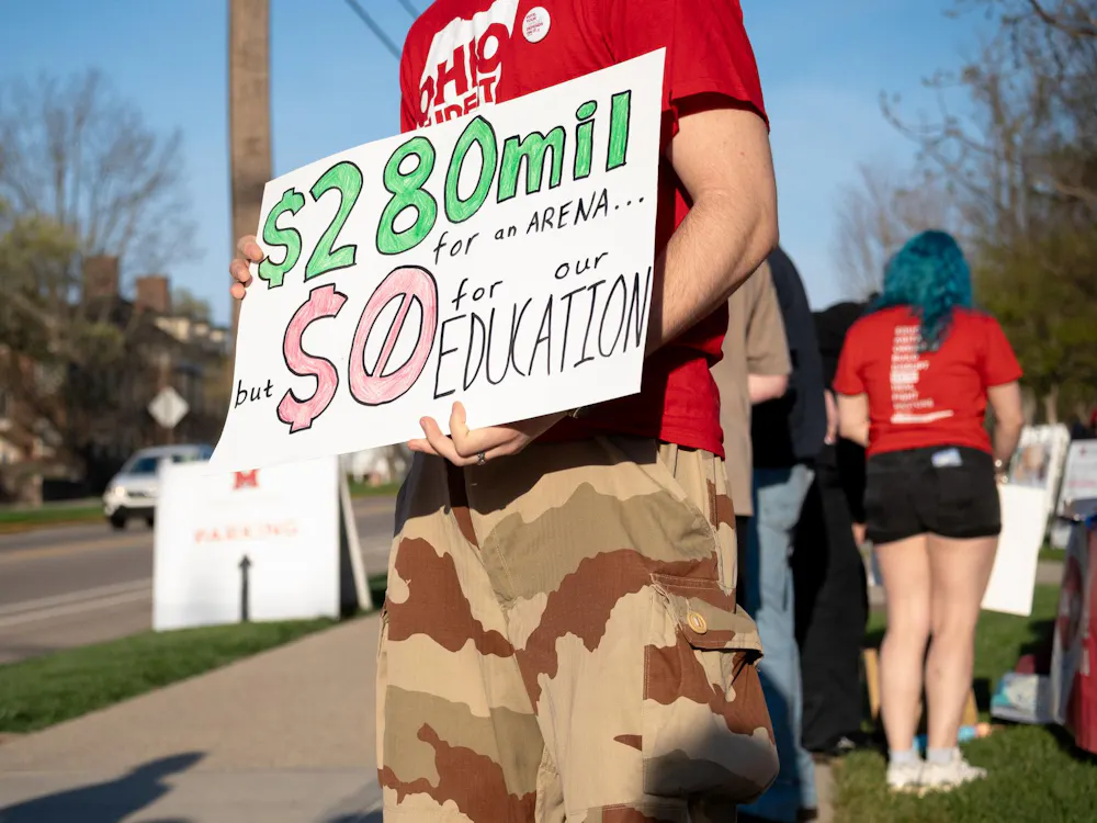 Student stands at the protest with a sign. Photo by Elise Hanna