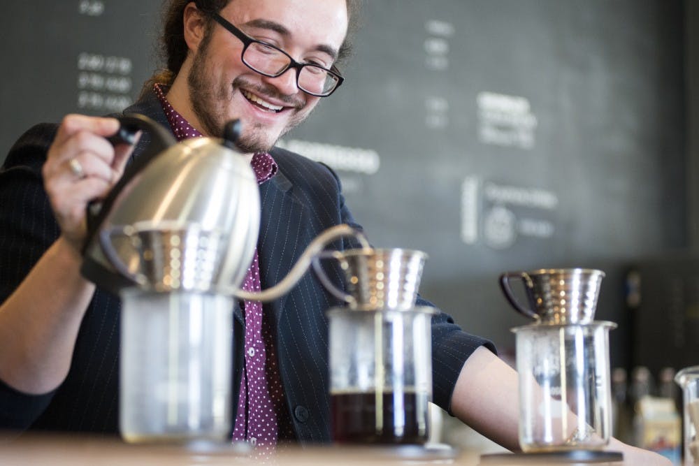 <p>Lansing resident Santino DallaVecchia laughs while interacting with a coworker and pours water through a filter to create a cup of coffee on Nov. 5, 2016 at Strange Matter Coffee in Lansing. Strange Matter Coffee uses the pour over method for each cup of hot coffee which brings out a full spectrum of flavors.</p>