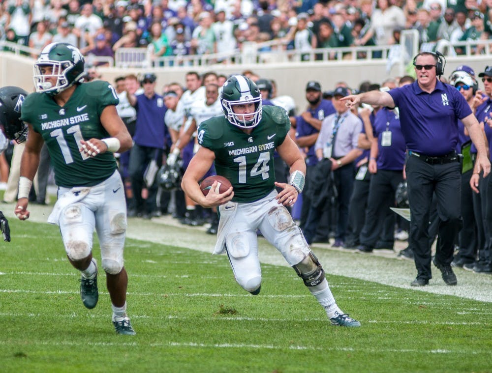 Junior quarterback Brian Lewerke (14) scrambles during the game against Northwestern on Oct. 6, 2018 at Spartan Stadium. The Spartans lost to the Wildcats 29-19.
