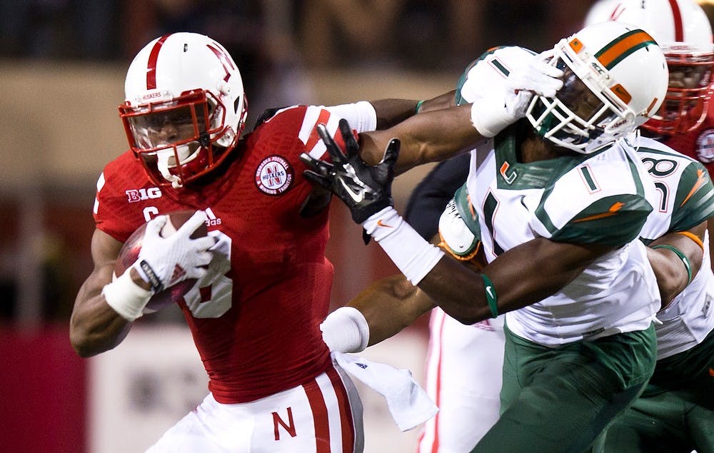 <p>Nebraska I Back Ameer Abdullah fends off Miami defensive back Artie Burns on Sept. 20, 2014, at Memorial Stadium in Lincoln, Neb. The Huskers defeated the Hurricanes, 41-31. Photo courtesy of Morgan Spiehs/The Daily Nebraskan </p>