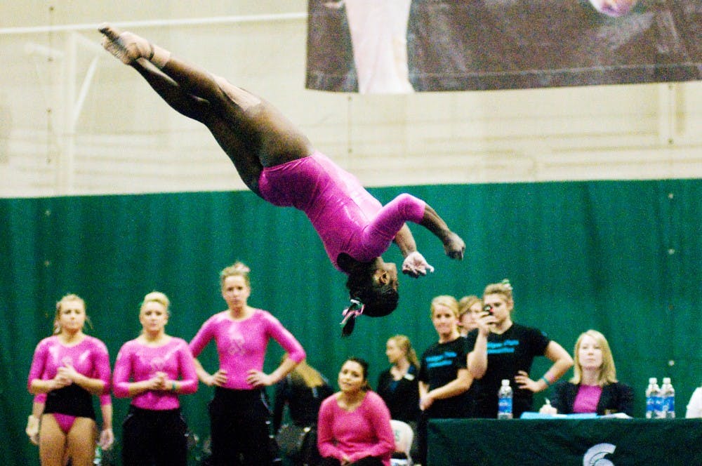 Teammates watch as sophomore Shanthi Teike performs her floor exercise during Saturday's meet against  Minnesota at Jenison Field House. Teike placed second in the all-around results with a score of 37.575. Lauren Wood/The State News
