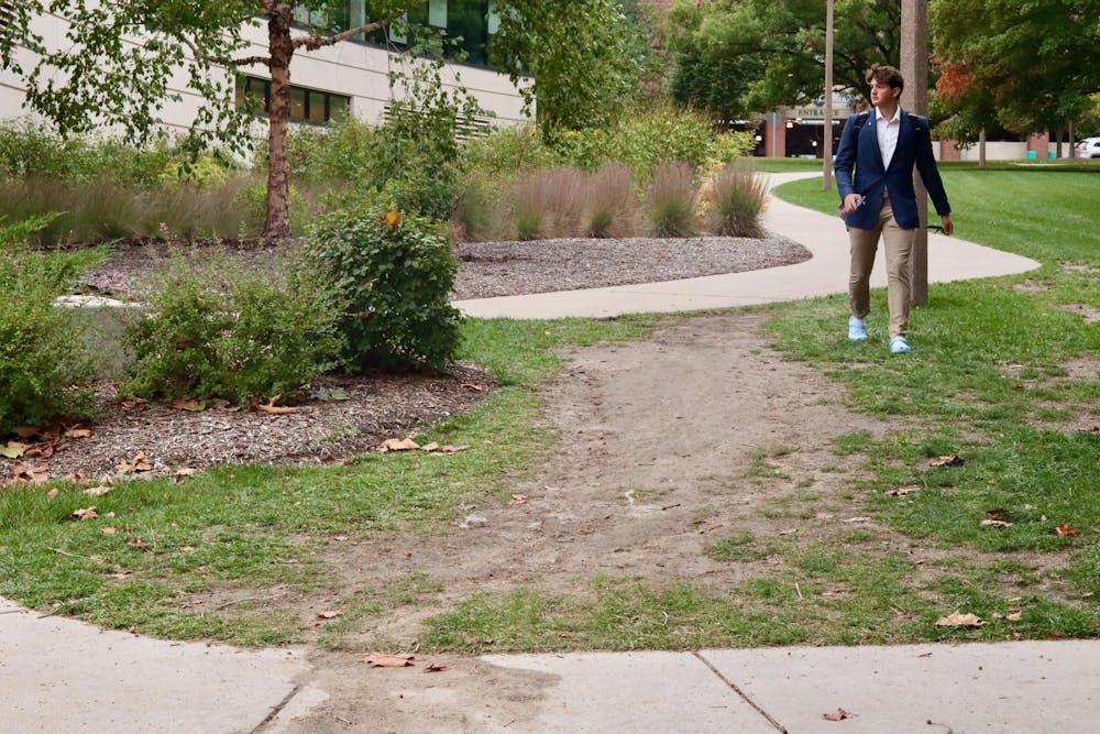 MSU student walks through a desire path located between Broad College of Business and Shaw Hall on Oct. 11, 2023.