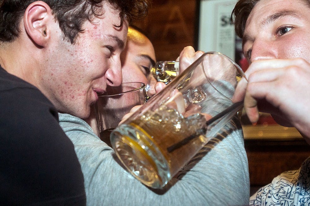 	<p>Bar patrons link arms to finish off a round of Long Island Iced Teas on Thursday, Feb. 14, 2013, at Crunchy&#8217;s, 254 W. Grand River Ave. The students shared several rounds drinks during the night out. </p>