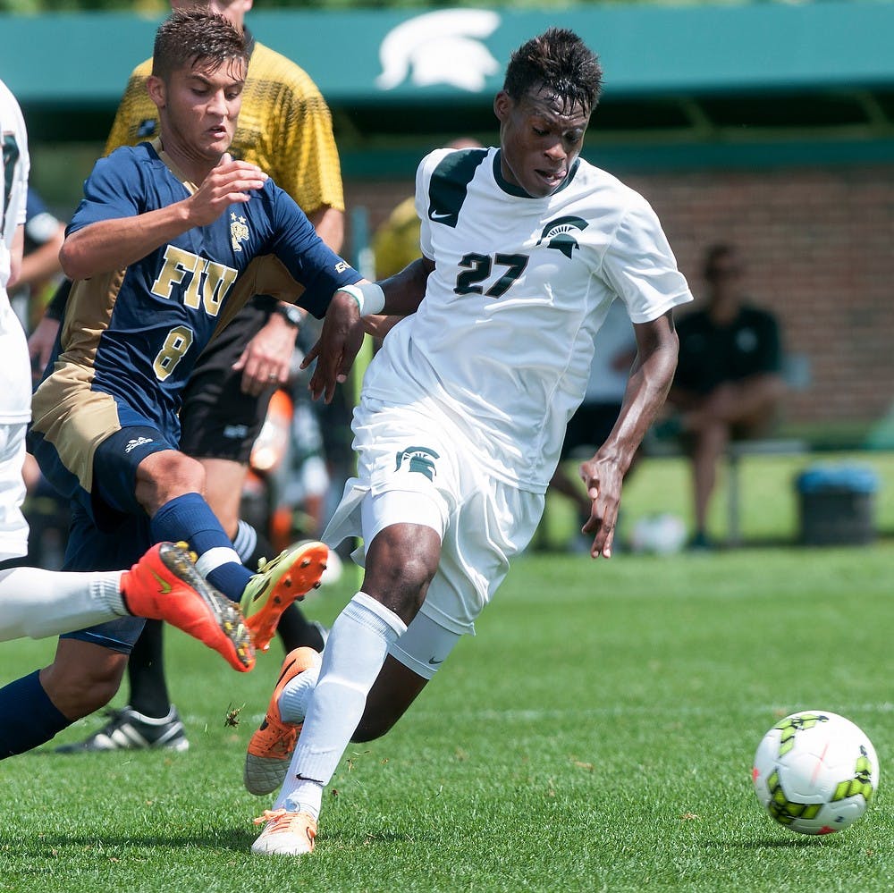 <p>Senior midfielder Fatai Alashe fights with Florida International midfielder Daniel Gonzalez for possession of the ball Aug. 31, 2014, at DeMartin Soccer Stadium at Old College Field. Raymond Williams/The State News</p>