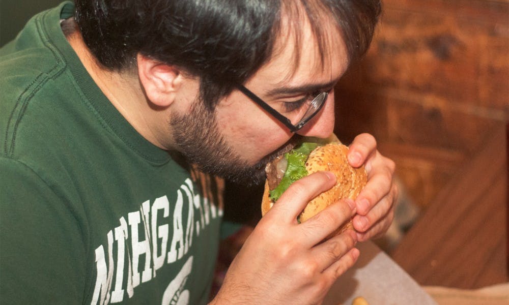 <p>Lansing resident Patrick Sandoval enjoys a burger on Sept. 3, 2014, at Crunchy's.</p>