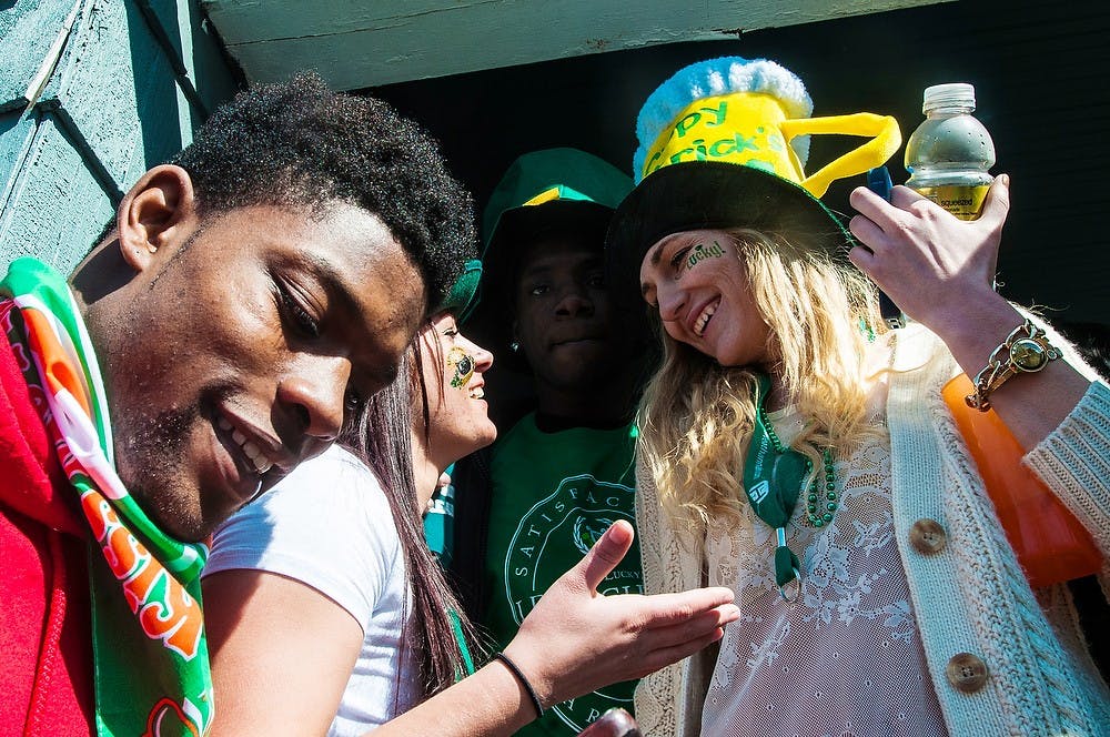 <p>Olivet College student Tyre Alexander mingles with Grand Valley State students Destiny Daniels, center, and Ashley Mamula, right, March, 17, 2014, outside a party on Collingwood Drive. Although St. Patrick's Day was on a Monday, a school day for MSU students, many students still found time to party. Erin Hampton/The State News</p>