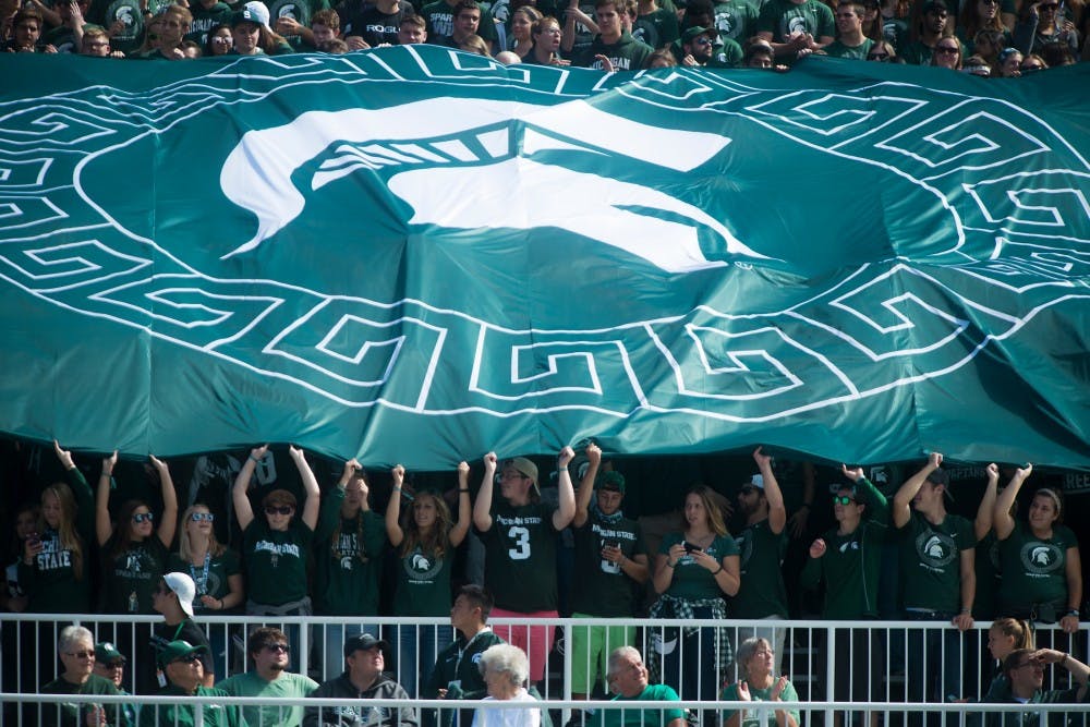 Students hold a flag and cheer during the first half of the game on Sept. 24, 2016 at Spartan Stadium. The Spartans were defeated by the Badgers, 30-6. 